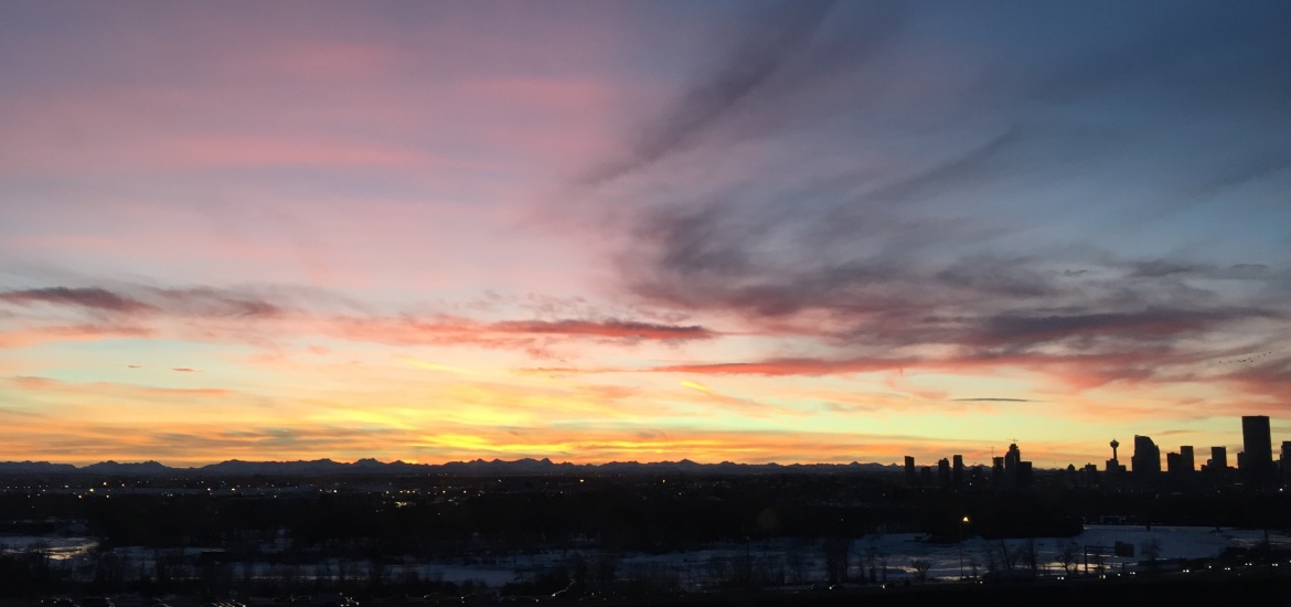 Calgary's skyline shadow over a sunset backdrop.