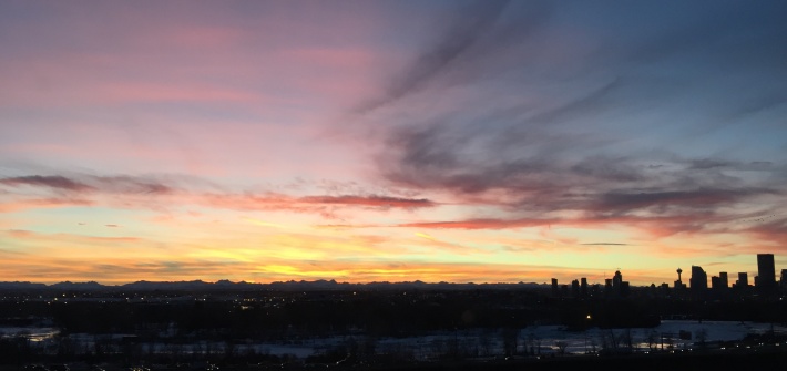Calgary's skyline shadow over a sunset backdrop.